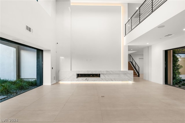 hallway with a towering ceiling and light tile patterned floors