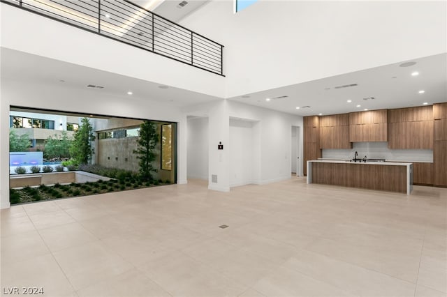 unfurnished living room featuring a towering ceiling and light tile patterned flooring