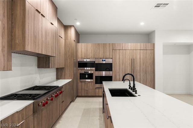 kitchen featuring light stone countertops, stainless steel appliances, and sink