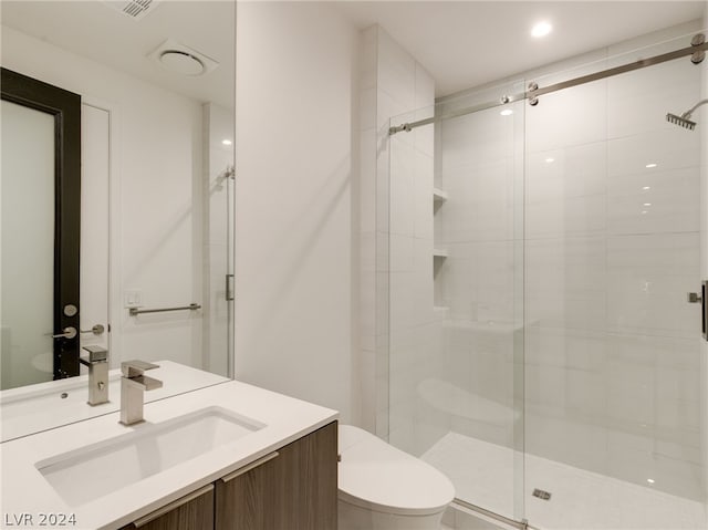 bathroom featuring vanity, toilet, and a shower with shower door