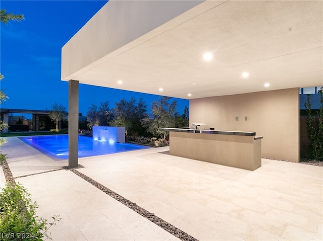 view of pool featuring a bar, a patio, and an outdoor kitchen