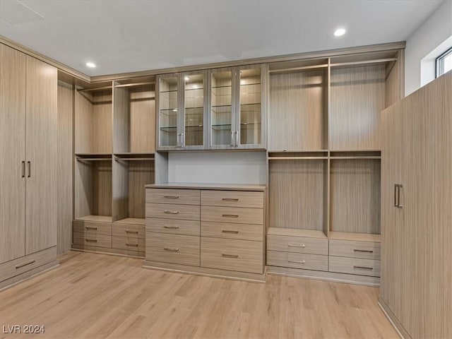 walk in closet with light hardwood / wood-style flooring