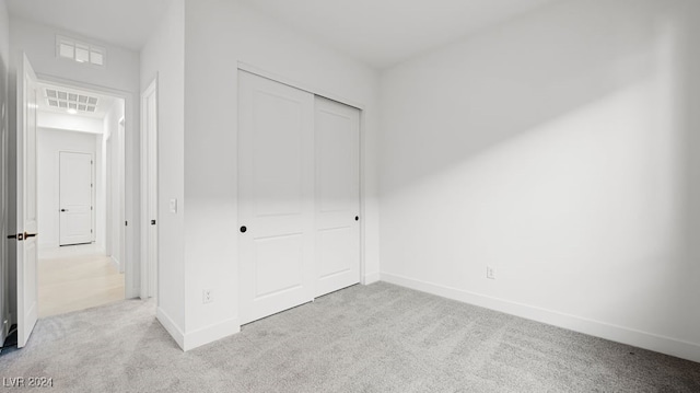 unfurnished bedroom with a closet and light colored carpet