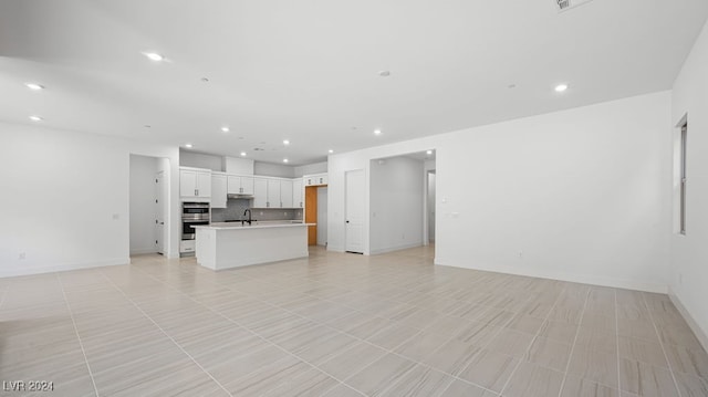 unfurnished living room featuring sink and light tile patterned floors