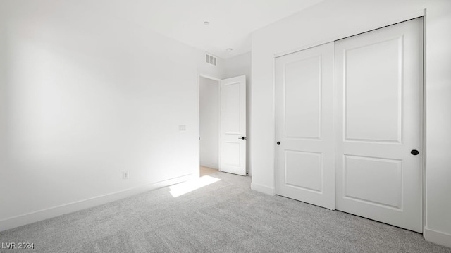 unfurnished bedroom with light carpet and a closet