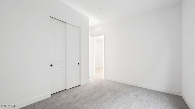 unfurnished bedroom featuring a closet and light colored carpet