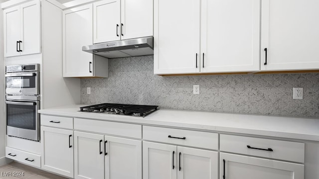 kitchen featuring light stone counters, white cabinetry, stainless steel appliances, and tasteful backsplash