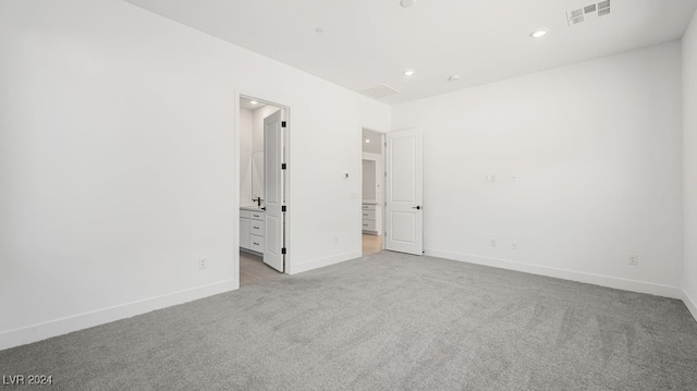 unfurnished bedroom with ensuite bath and light colored carpet