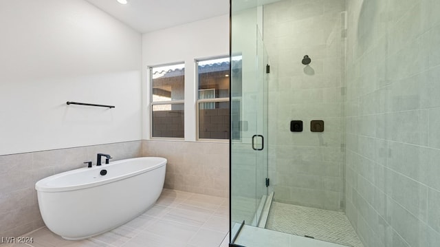 bathroom with shower with separate bathtub, tile patterned floors, and tile walls