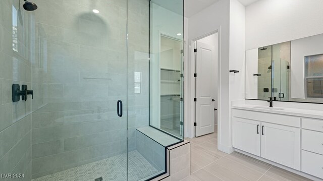 bathroom featuring tile patterned flooring, an enclosed shower, and vanity