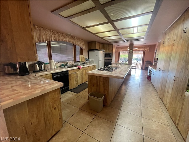 kitchen with a kitchen island, coffered ceiling, light tile flooring, stainless steel appliances, and tile countertops