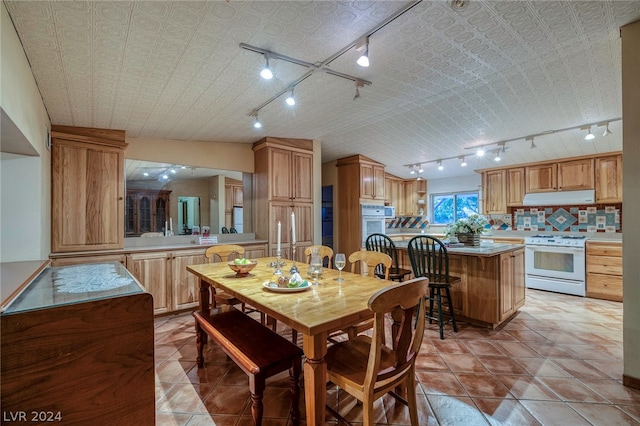 tiled dining space with lofted ceiling and track lighting