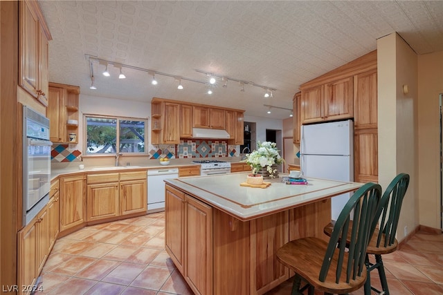 kitchen with white appliances, a kitchen island, lofted ceiling, decorative backsplash, and a breakfast bar area