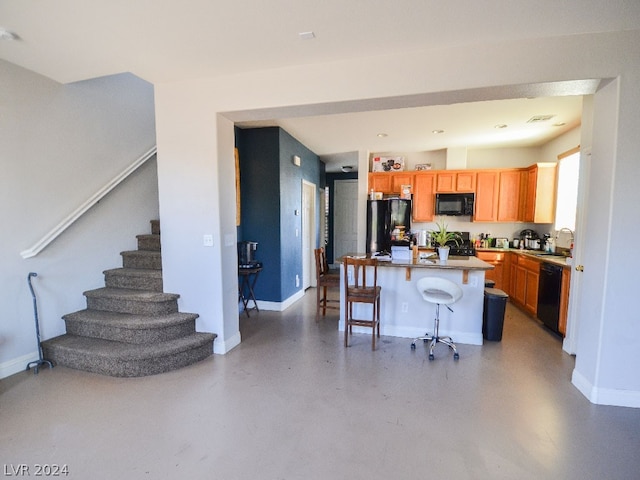 kitchen with a breakfast bar, black appliances, sink, and a center island