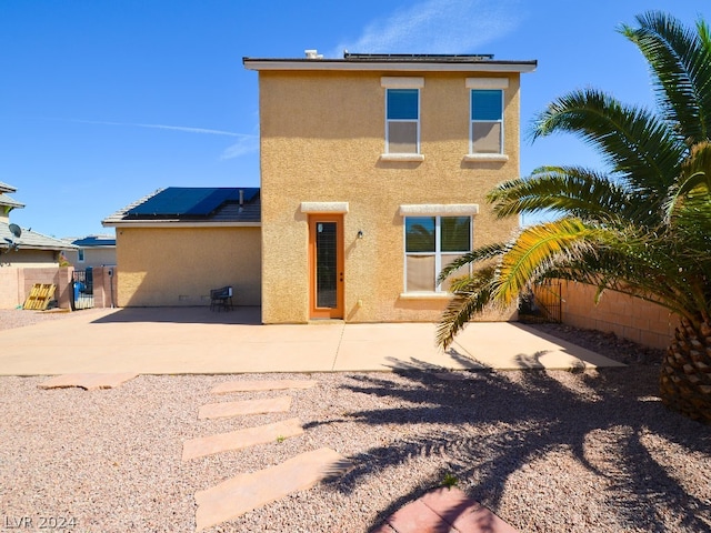 back of property with a patio area and solar panels