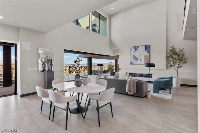 dining space with a high ceiling, light tile patterned floors, and a wealth of natural light