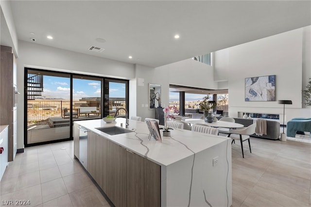 kitchen featuring a center island with sink, light stone countertops, sink, and a wealth of natural light