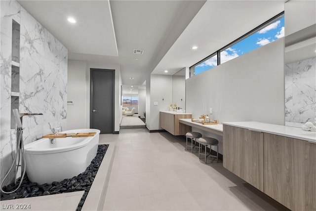 bathroom with vanity, a bathtub, tile patterned floors, and tile walls