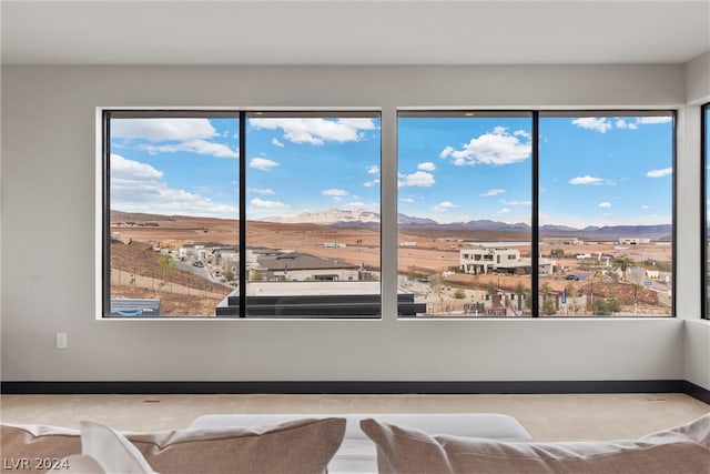 interior space with a mountain view, light colored carpet, and multiple windows