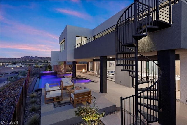 patio terrace at dusk with an outdoor living space and a fenced in pool