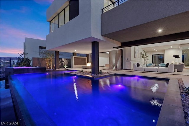 pool at dusk featuring an outdoor living space and a patio