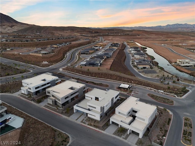 aerial view at dusk featuring a water and mountain view