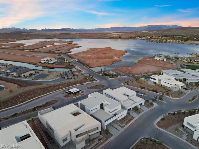 aerial view at dusk featuring a water and mountain view