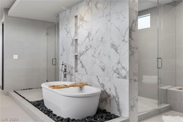 bathroom featuring shower with separate bathtub and tile walls