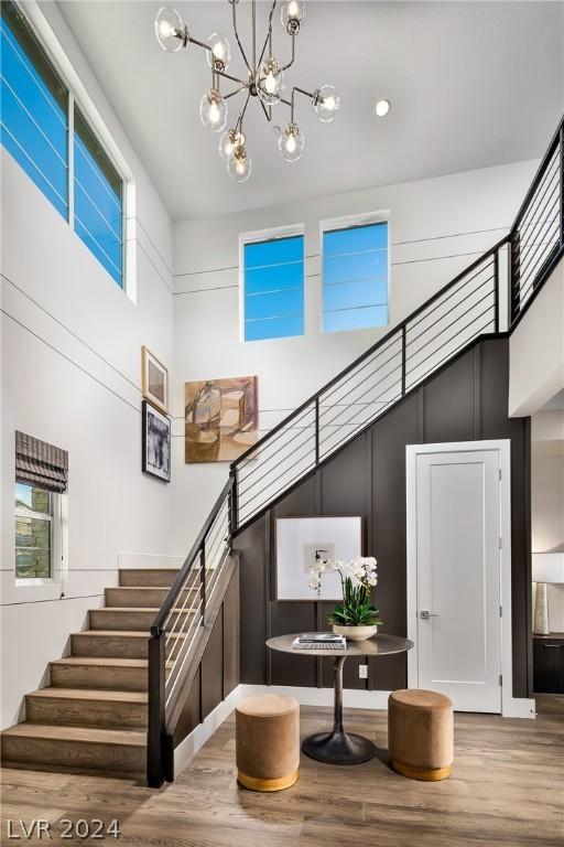 staircase featuring hardwood / wood-style floors, a towering ceiling, and an inviting chandelier