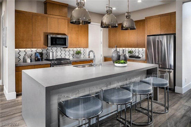 kitchen featuring sink, an island with sink, hardwood / wood-style floors, and high end appliances