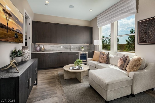 living room featuring light hardwood / wood-style floors, sink, and beverage cooler