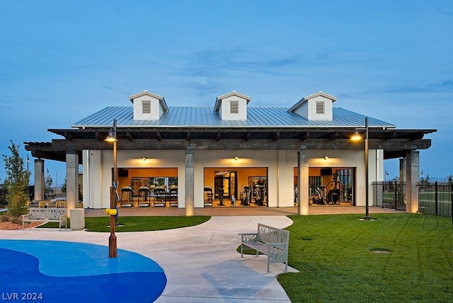 back house at dusk featuring a yard, a patio, and ceiling fan