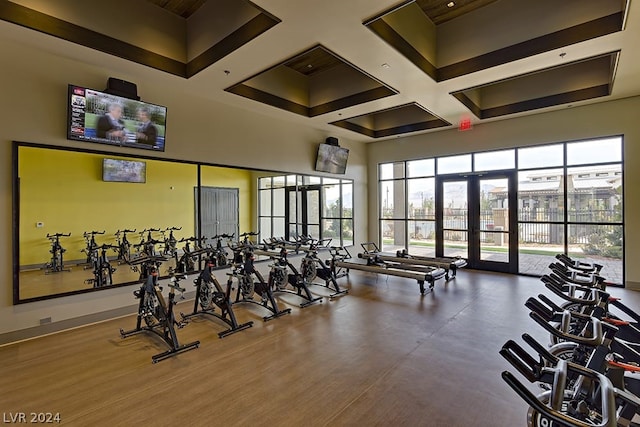 exercise room featuring coffered ceiling and a high ceiling