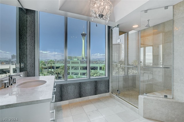 bathroom featuring an inviting chandelier, tile patterned floors, a shower with door, and vanity