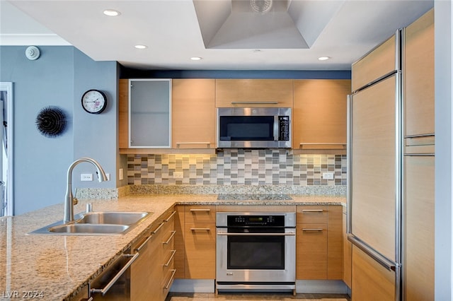 kitchen featuring light stone countertops, sink, stainless steel appliances, and tasteful backsplash