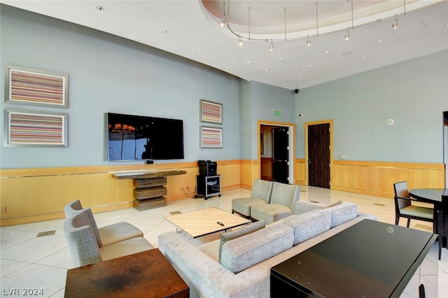 living room with rail lighting, a towering ceiling, and light tile patterned floors