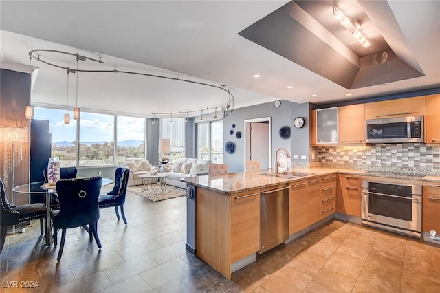 kitchen with tasteful backsplash, sink, kitchen peninsula, stainless steel appliances, and light stone countertops