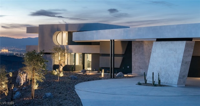 back house at dusk with a patio and a mountain view