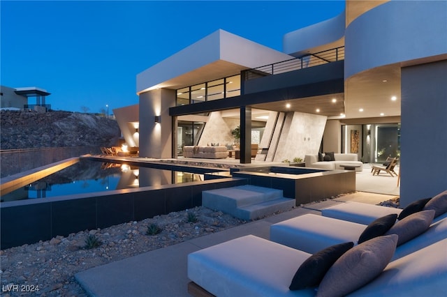 pool at dusk featuring an in ground hot tub, an outdoor living space, and a patio area