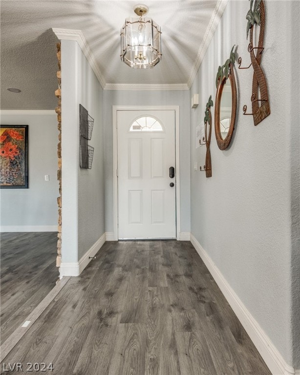 entrance foyer with dark hardwood / wood-style floors, a textured ceiling, an inviting chandelier, and crown molding