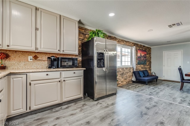 kitchen featuring light stone counters, light hardwood / wood-style floors, backsplash, crown molding, and stainless steel fridge