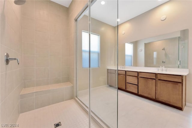 bathroom with a tile shower and vanity