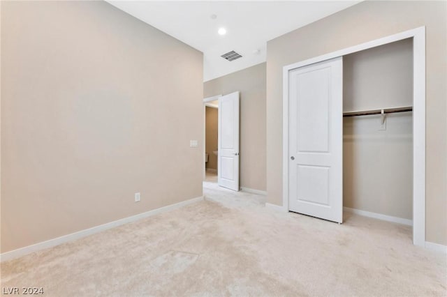 unfurnished bedroom featuring light carpet and a closet