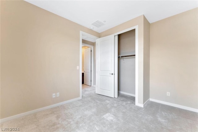 unfurnished bedroom with light colored carpet and a closet