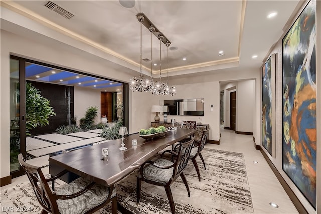 dining room featuring an inviting chandelier, a raised ceiling, and light tile floors