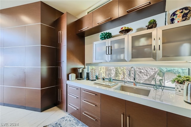 kitchen with modern cabinets, glass insert cabinets, light countertops, and a sink