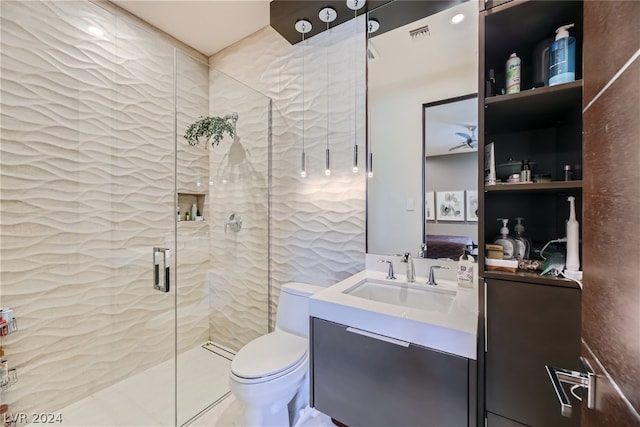 bathroom with a shower with door, tile flooring, vanity with extensive cabinet space, and toilet