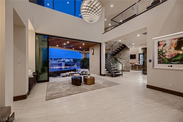 foyer entrance featuring a towering ceiling, stairs, baseboards, and recessed lighting