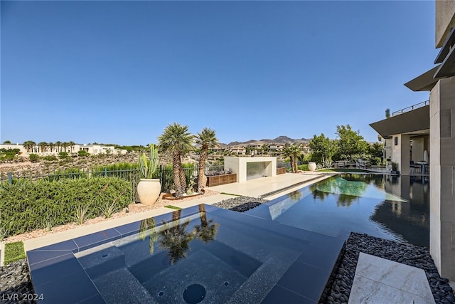 outdoor pool featuring fence, a mountain view, and a patio