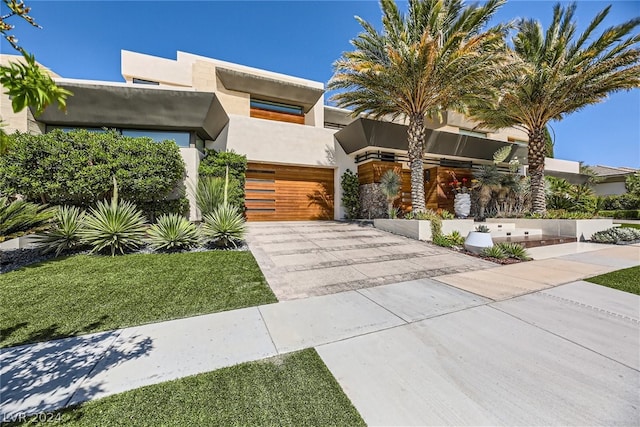 view of front of house featuring a garage, concrete driveway, and stucco siding